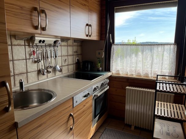 Küche Moderne Küchenzeile mit Spüle, Herd und Fenster, helles Holzdesign.